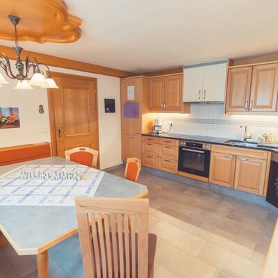 The Farm House kitchen is equipped with wooden cabinets, a stovetop, oven, and dishwasher, with an adjacent dining area featuring a wooden table and corner bench.
