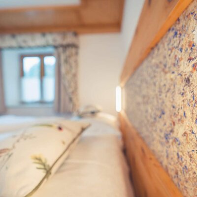 The Farm House bedroom features a wooden bed with a headboard made from pressed flowers and integrated lighting.