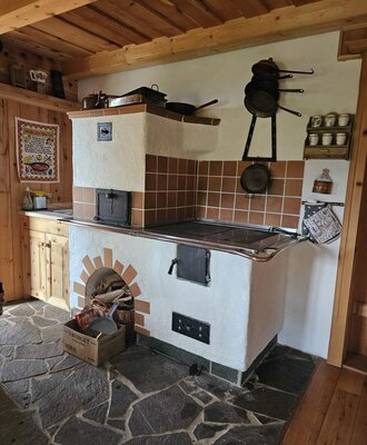 The traditional kitchen of the Bed and Breakfast featuring a wood-burning stove with an oven and a stone floor.