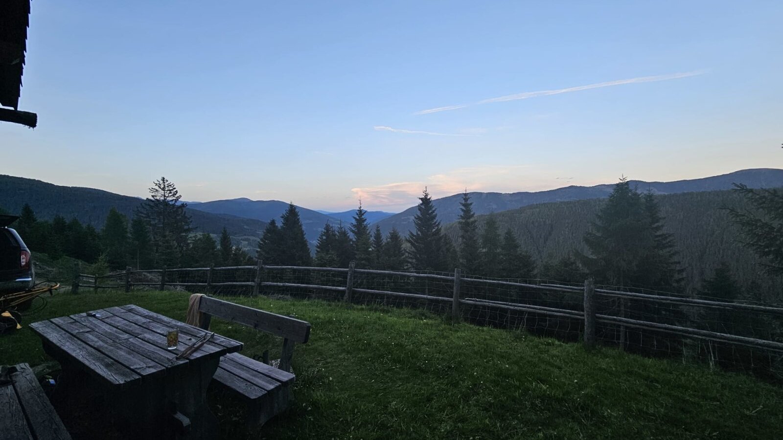 Outdoor area of the Bed and Breakfast with a wooden table, benches, and a view of the mountains and forests.