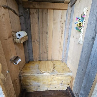 Outdoor toilet of the Bed and Breakfast, made of wood with a toilet paper holder.