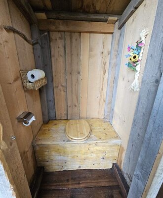 Outdoor toilet of the Bed and Breakfast, made of wood with a toilet paper holder.