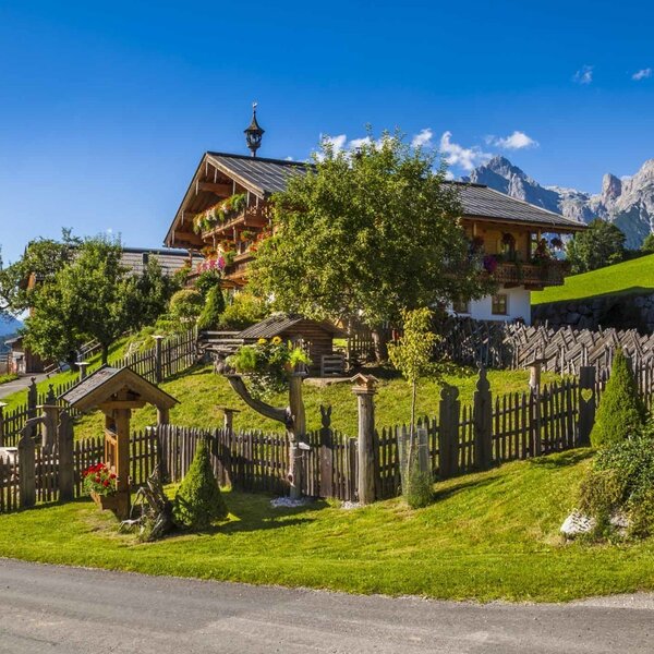 The Farm House exterior, featuring traditional wooden architecture, a landscaped garden, and views of the surrounding mountains.