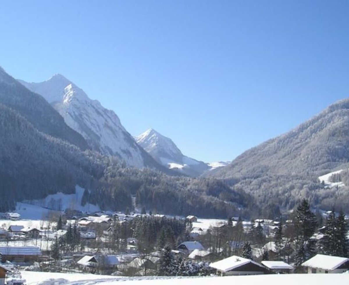 The snow-covered village and surrounding mountains, showcasing the setting of the Farm House.