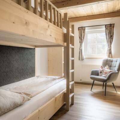 Bedroom in the Alm featuring a wooden bunk bed, a window, and an armchair.