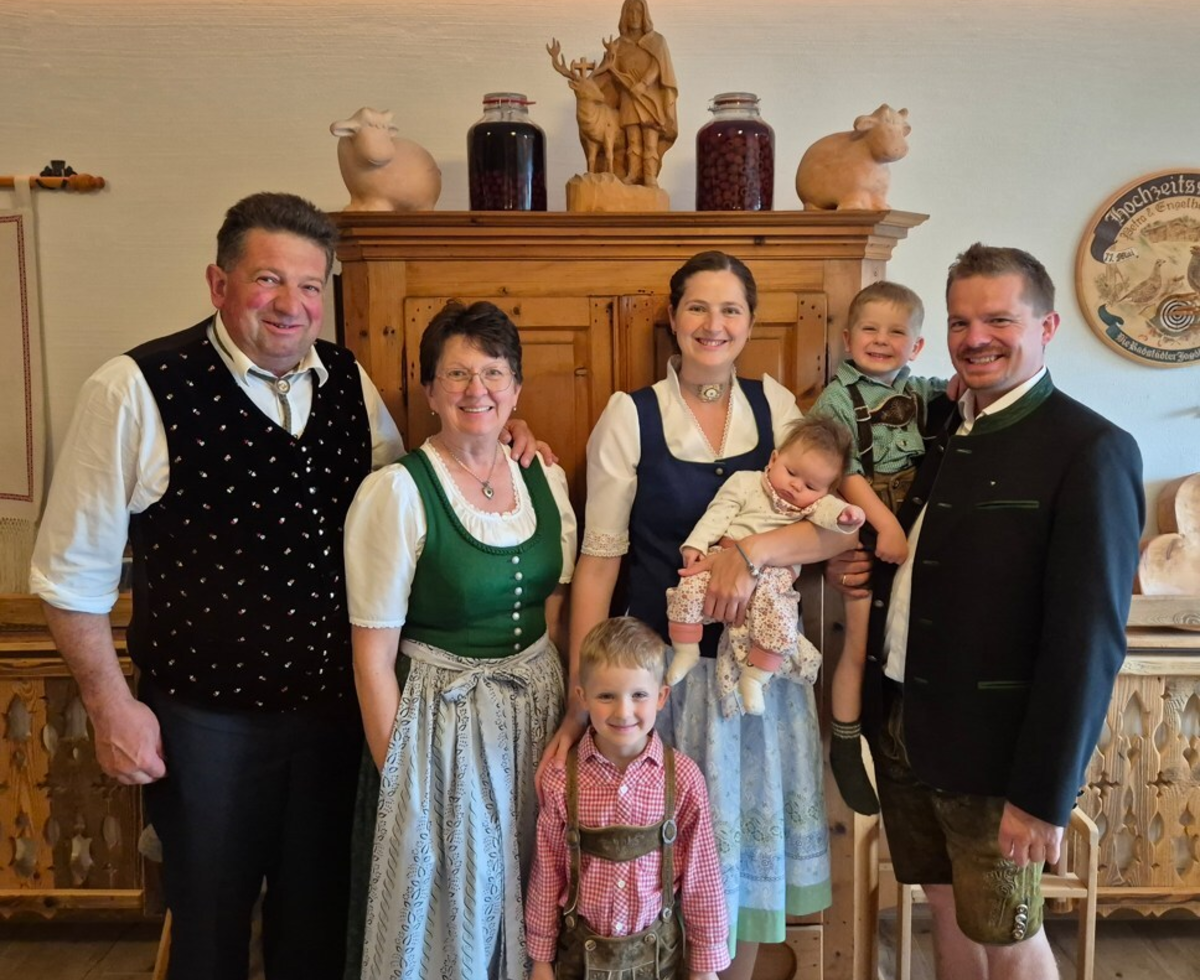 The welcoming host family of the farmhouse greeting guests in traditional attire.