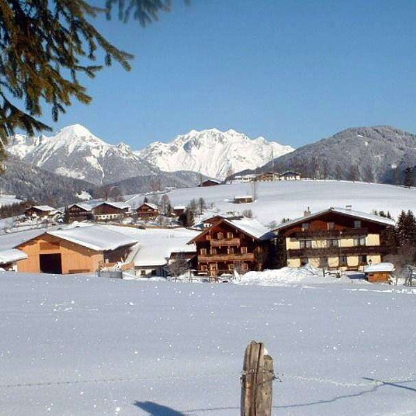 The Farm House complex, featuring a barn and other buildings, covered in snow and surrounded by mountains.