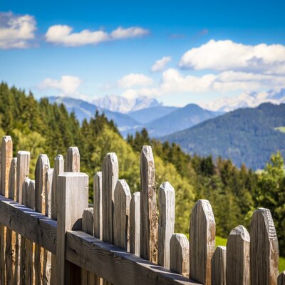 A traditional wooden fence at the farmhouse overlooks the forested hills and distant mountains.