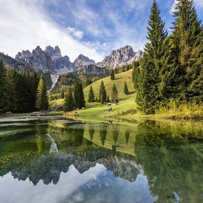 A mountain lake reflecting the surrounding peaks and evergreen forests, showcasing the natural landscape near the farm house.