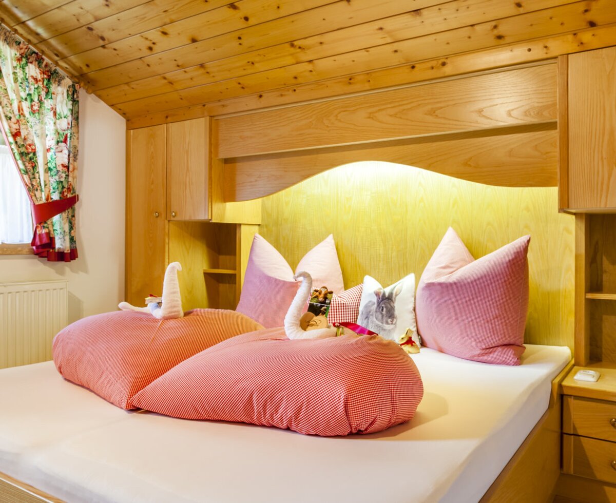 Double bedroom in the Farm House apartment with wooden built-in cabinets and a window.