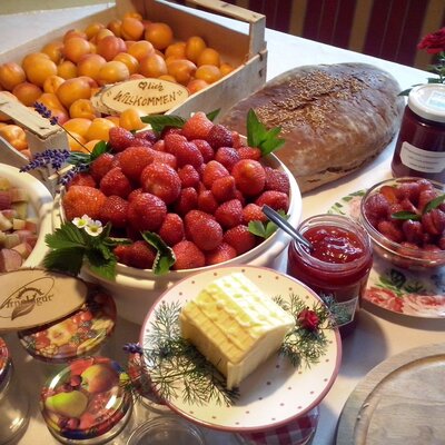 A table at the Farm House displaying fresh apricots, strawberries, rhubarb, bread, jams, and butter.