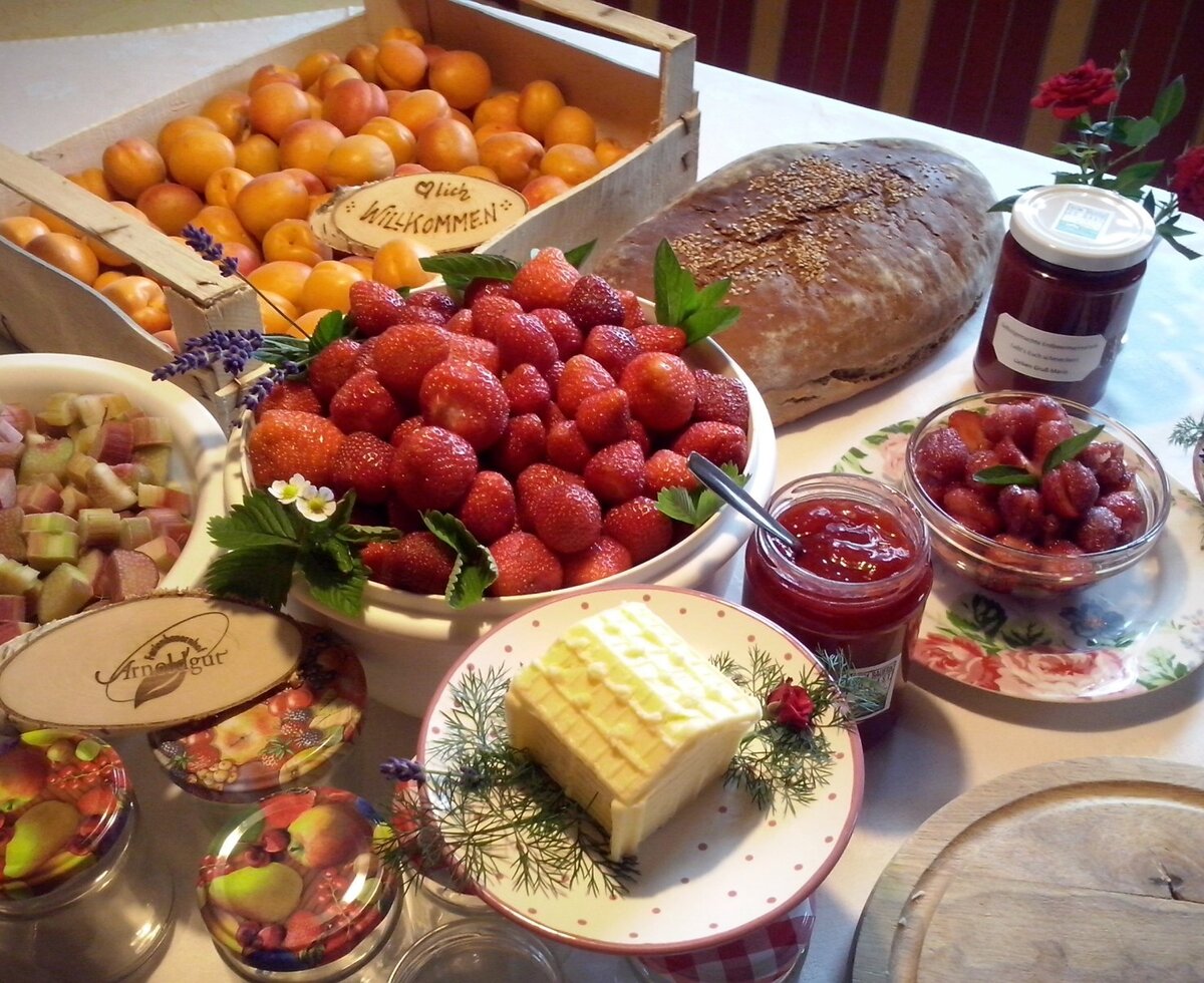 A table at the Farm House displaying fresh apricots, strawberries, rhubarb, bread, jams, and butter.