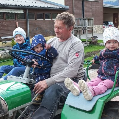 Children and an adult enjoying a ride on a green tractor at the Farm House.