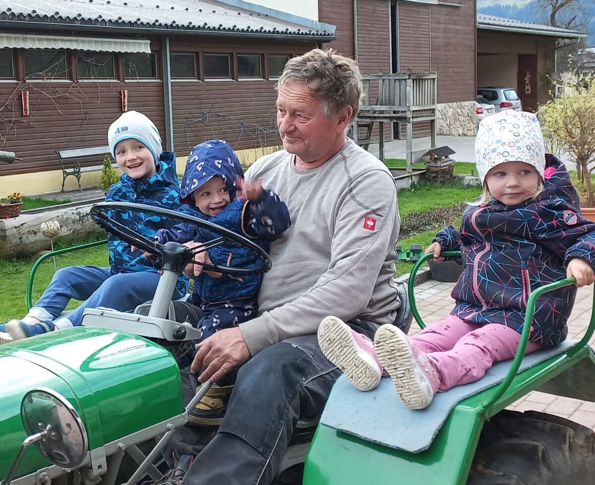 Children and an adult enjoying a ride on a green tractor at the Farm House.