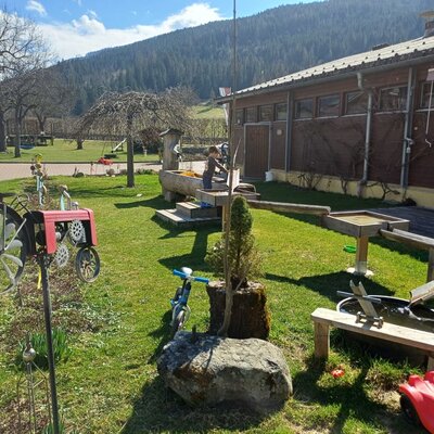 The outdoor area of the farmhouse, featuring a water play structure, sandpit, and play equipment.