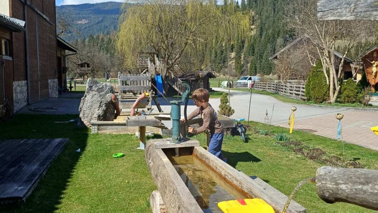 Children's play area at the farmhouse with a water trough and hand pump.