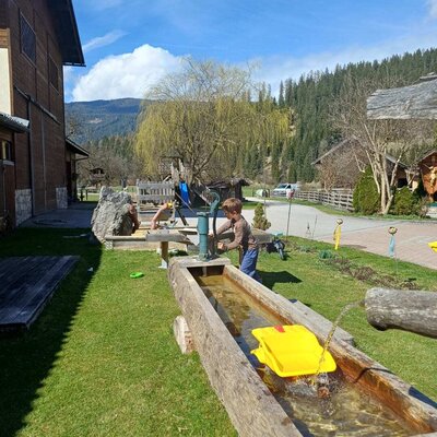 Children's play area at the farmhouse with a water trough and hand pump.