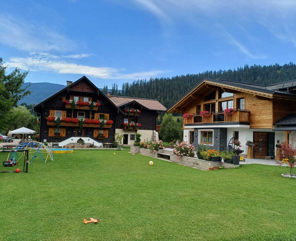 The farmhouse buildings with a large lawn and a children's playground.