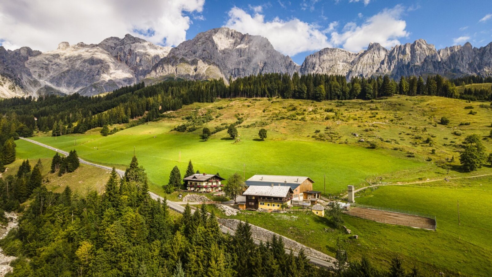 The idyllic farmhouse set amidst lush green meadows against the impressive backdrop of the Hochkönig mountains.