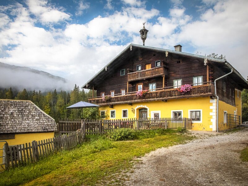 The farmhouse dating back to 1679 with its charming wooden facade, flower-adorned balcony, and cozy terrace.