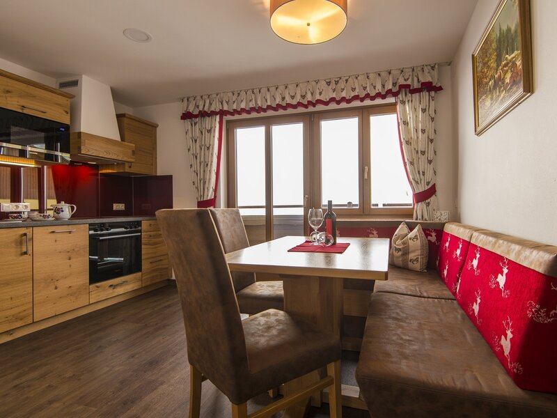 The farmhouse kitchen and dining area, equipped with wooden cabinets, an oven, a dining table, and bench seating next to a window.