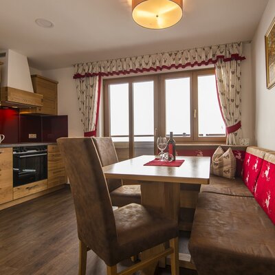 The farmhouse kitchen and dining area, equipped with wooden cabinets, an oven, a dining table, and bench seating next to a window.
