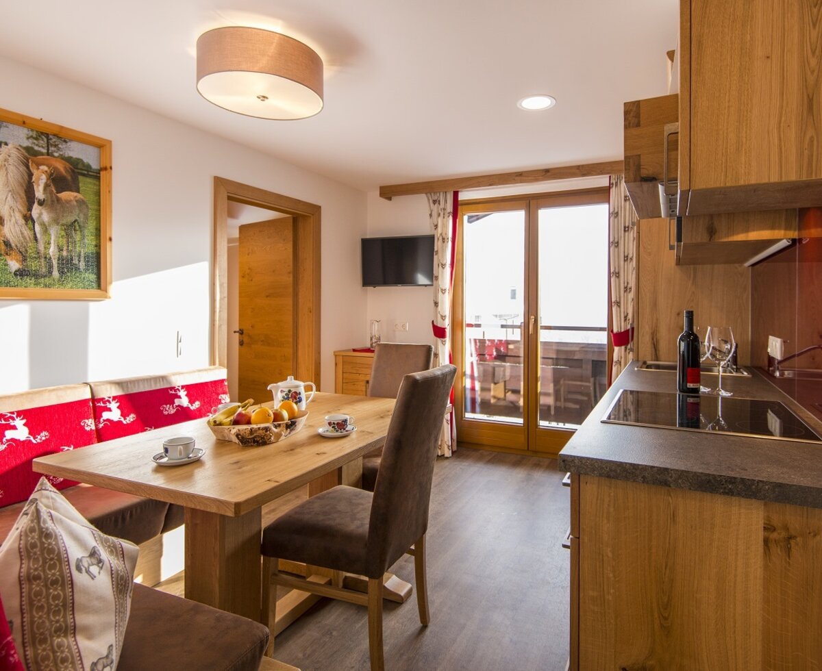 The farm house features a combined kitchen and dining area with a wooden table, traditional bench seating, an integrated hob, and balcony access.