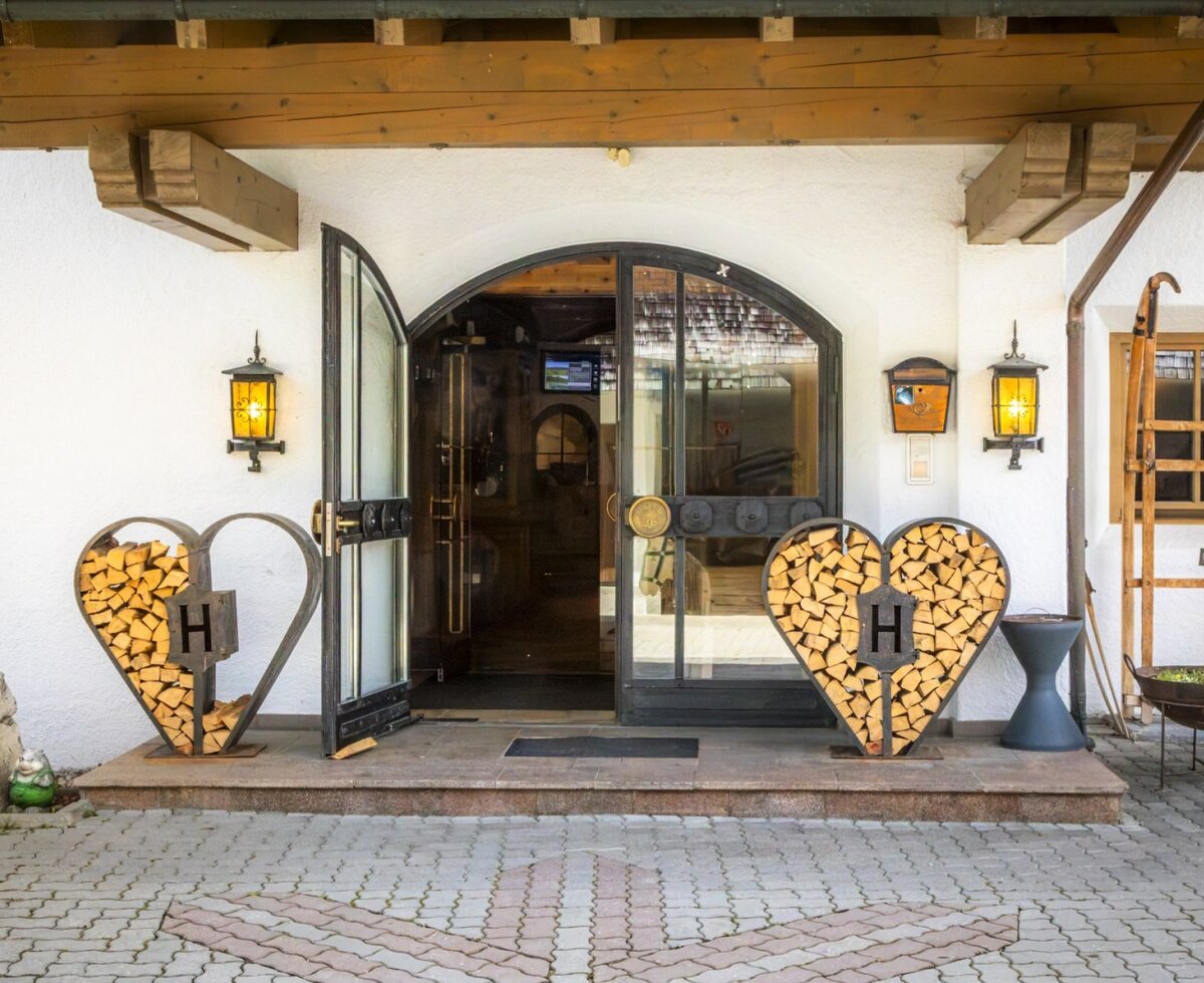 The farms's inviting entrance featuring heart-shaped wood stacks, warm wall lanterns, and traditional charm.