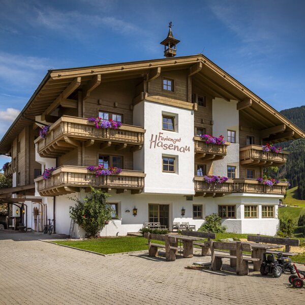 The farm's charming alpine-style exterior, featuring flower-decked wooden balconies and an inviting outdoor seating area.