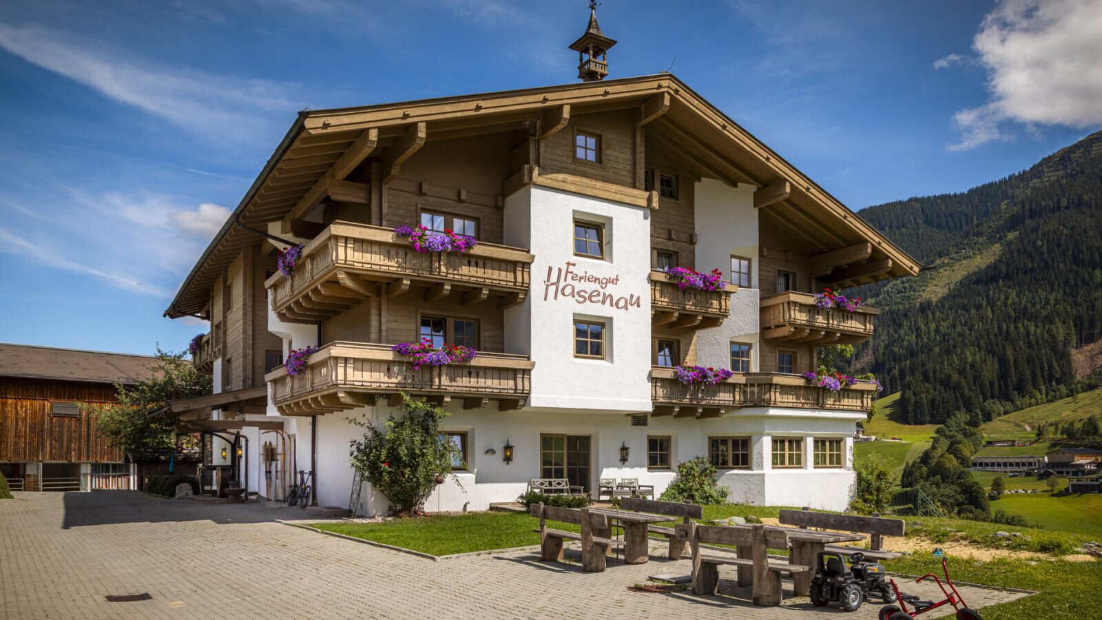 The farm's charming alpine-style exterior, featuring flower-decked wooden balconies and an inviting outdoor seating area.