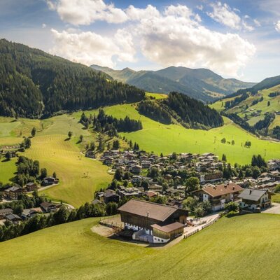 The idyllically situated farmhouse surrounded by lush green meadows, offering scenic views of the surrounding mountains.