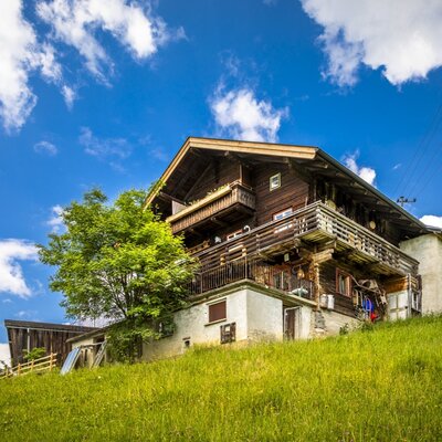 The exterior of the multi-story wooden vacation rental, featuring several balconies and situated on a grassy hillside.