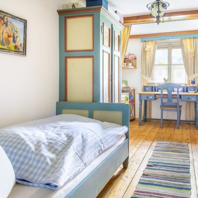Single bedroom in the vacation rental with a painted wooden bed, a matching wardrobe, and a desk with a chair positioned by the window.