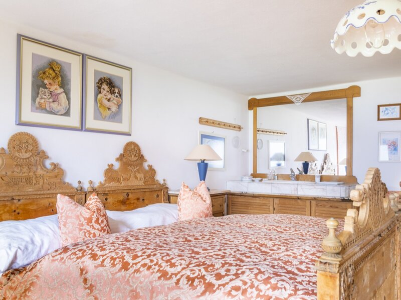 Double bedroom in the vacation rental featuring a carved wooden bed and a vanity area with a mirror and washbasin.