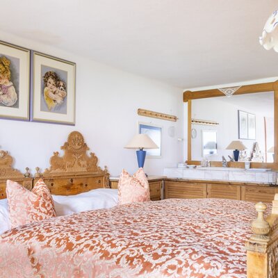 Double bedroom in the vacation rental featuring a carved wooden bed and a vanity area with a mirror and washbasin.