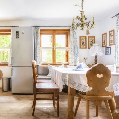 The vacation rental's dining area and kitchen are equipped with a wooden table, bench seating, and a refrigerator.