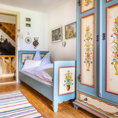 Single bedroom in the vacation rental, featuring a painted wooden bed, matching wardrobe, and access to an internal staircase.