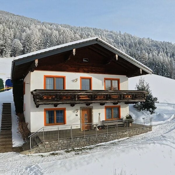 The Englbrecht farmhouse, with its traditional wooden balcony and ground-floor terrace, set against snow-covered hills.