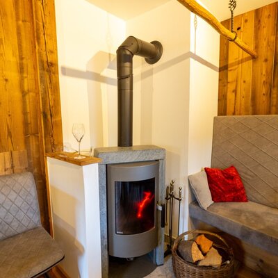 Modern wood-burning stove with burning fire, wood basket, and seating in the Bed and Breakfast.