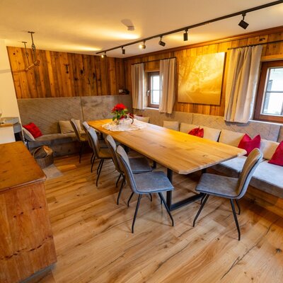 Dining area at the Bed and Breakfast with a long wooden table, bench seating, wood-burning stove, and wooden walls.
