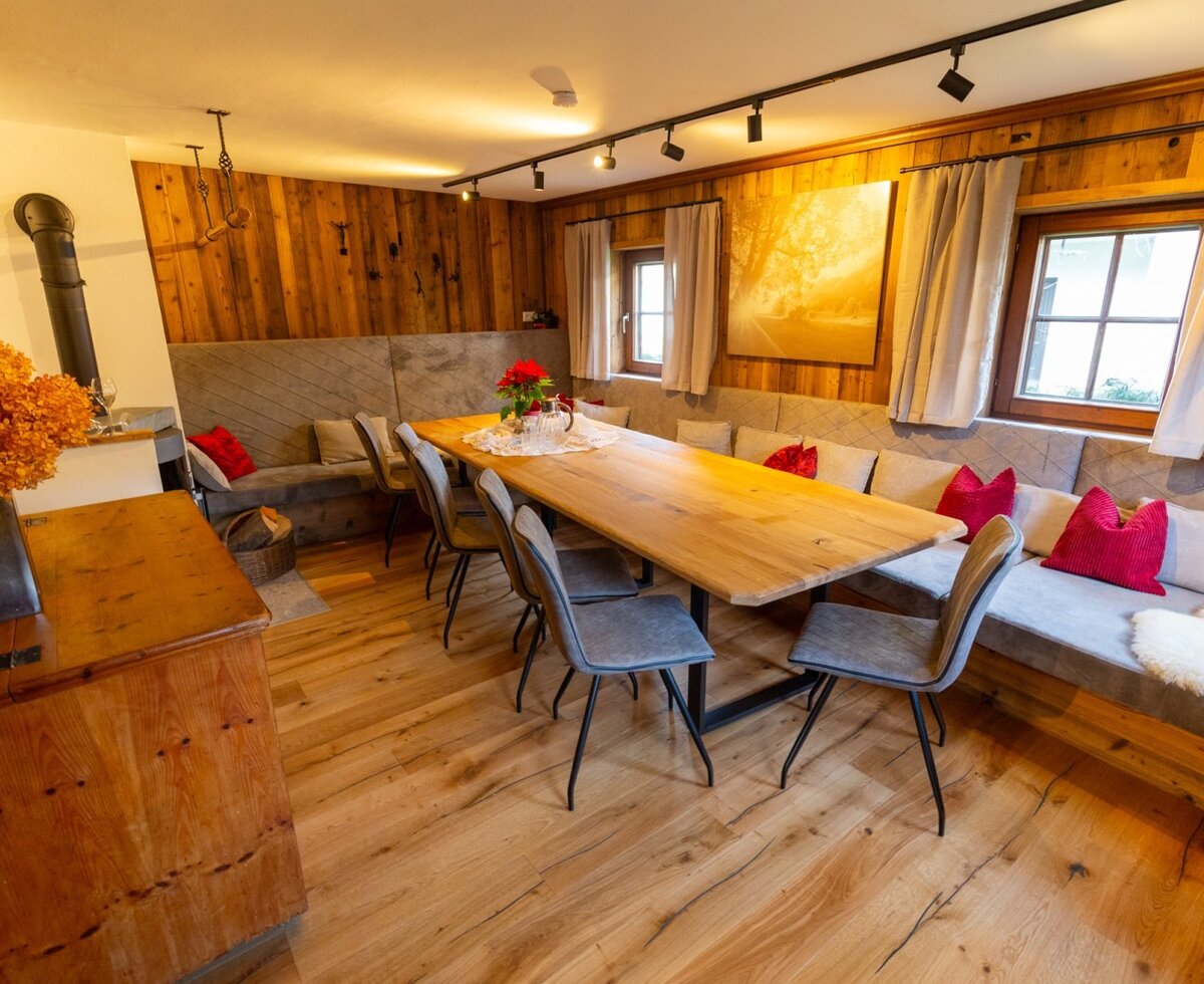 Dining area at the Bed and Breakfast with a long wooden table, bench seating, wood-burning stove, and wooden walls.