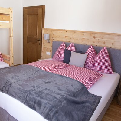 Bedroom in the Farm House featuring a double bed, a bunk bed, and wooden paneling.