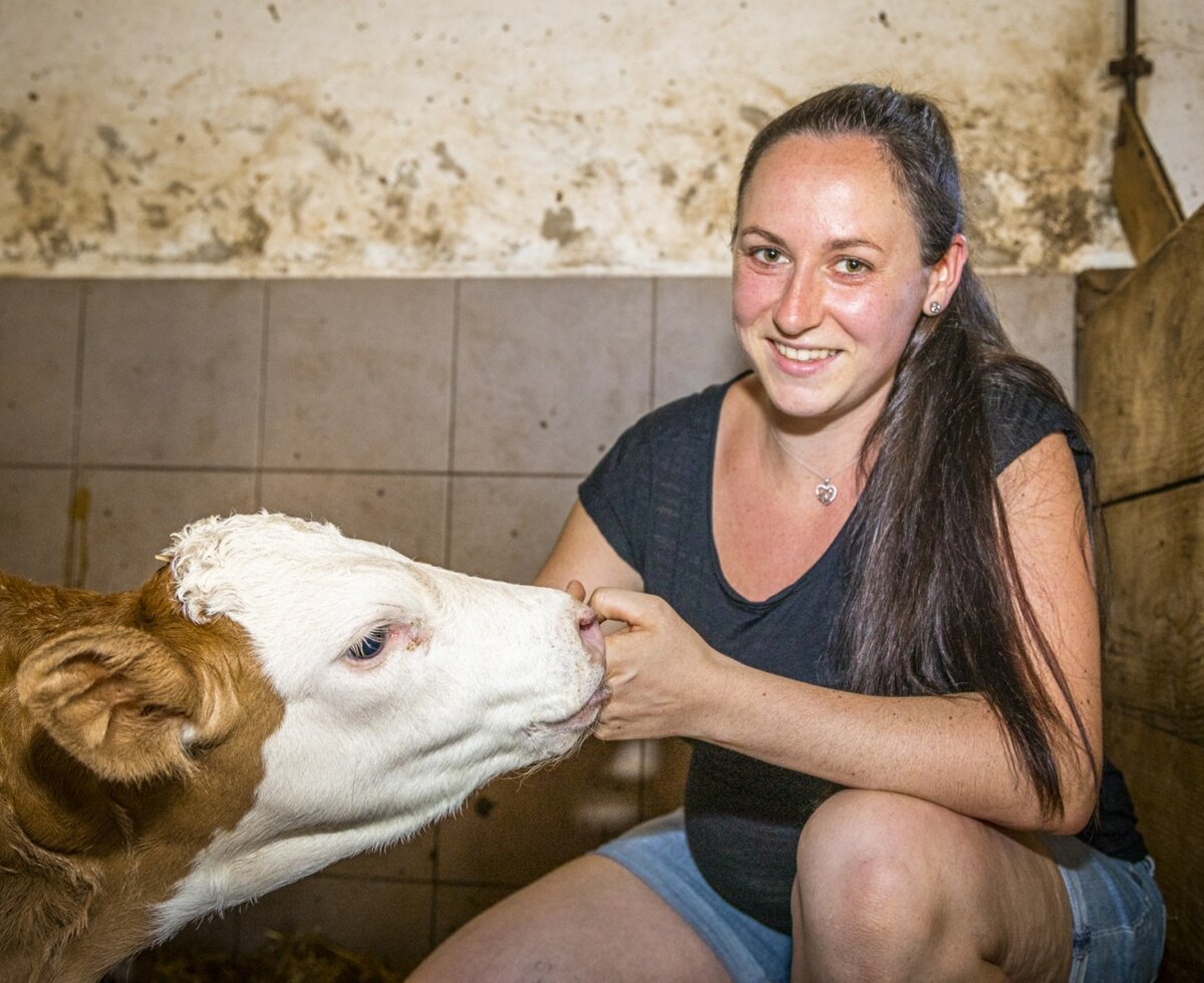 A woman interacts with a young calf at the farm house.