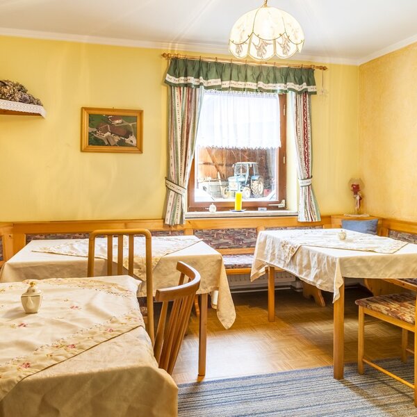 The recreation room of the Farm House holiday apartment, featuring multiple dining tables and built-in bench seating.