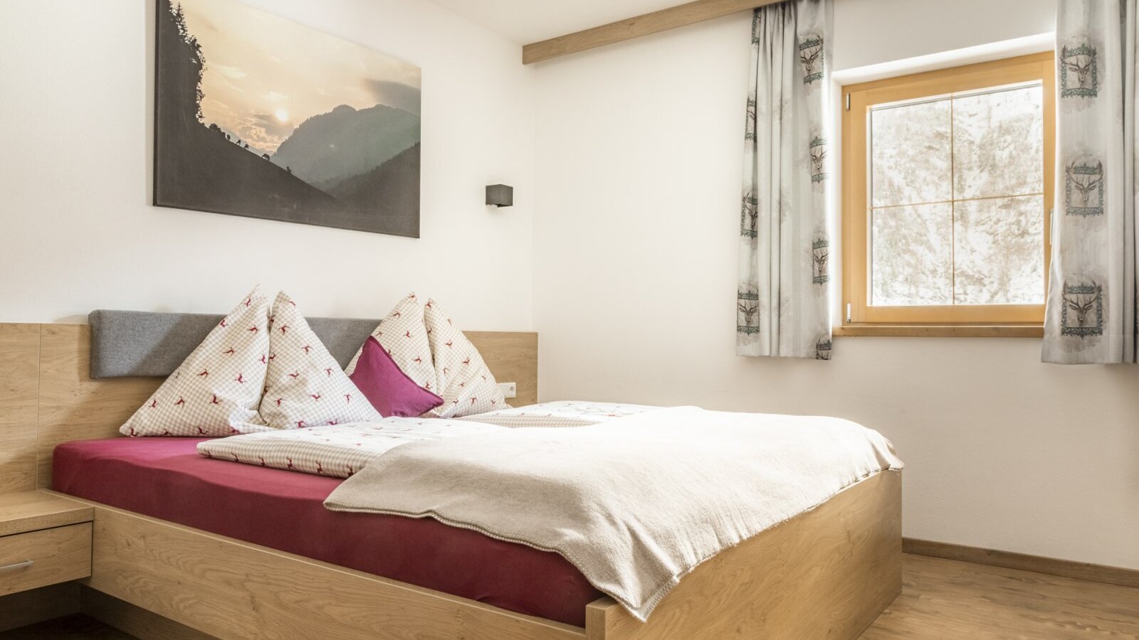 Bedroomm with a double bed, nightstand, and window with curtains.