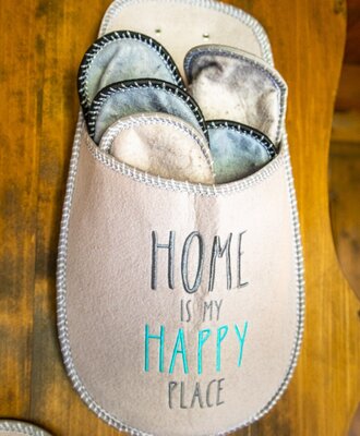 A felt slipper holder displaying "HOME IS MY HAPPY PLACE" provides multiple pairs of slippers for guests at the Farm House.