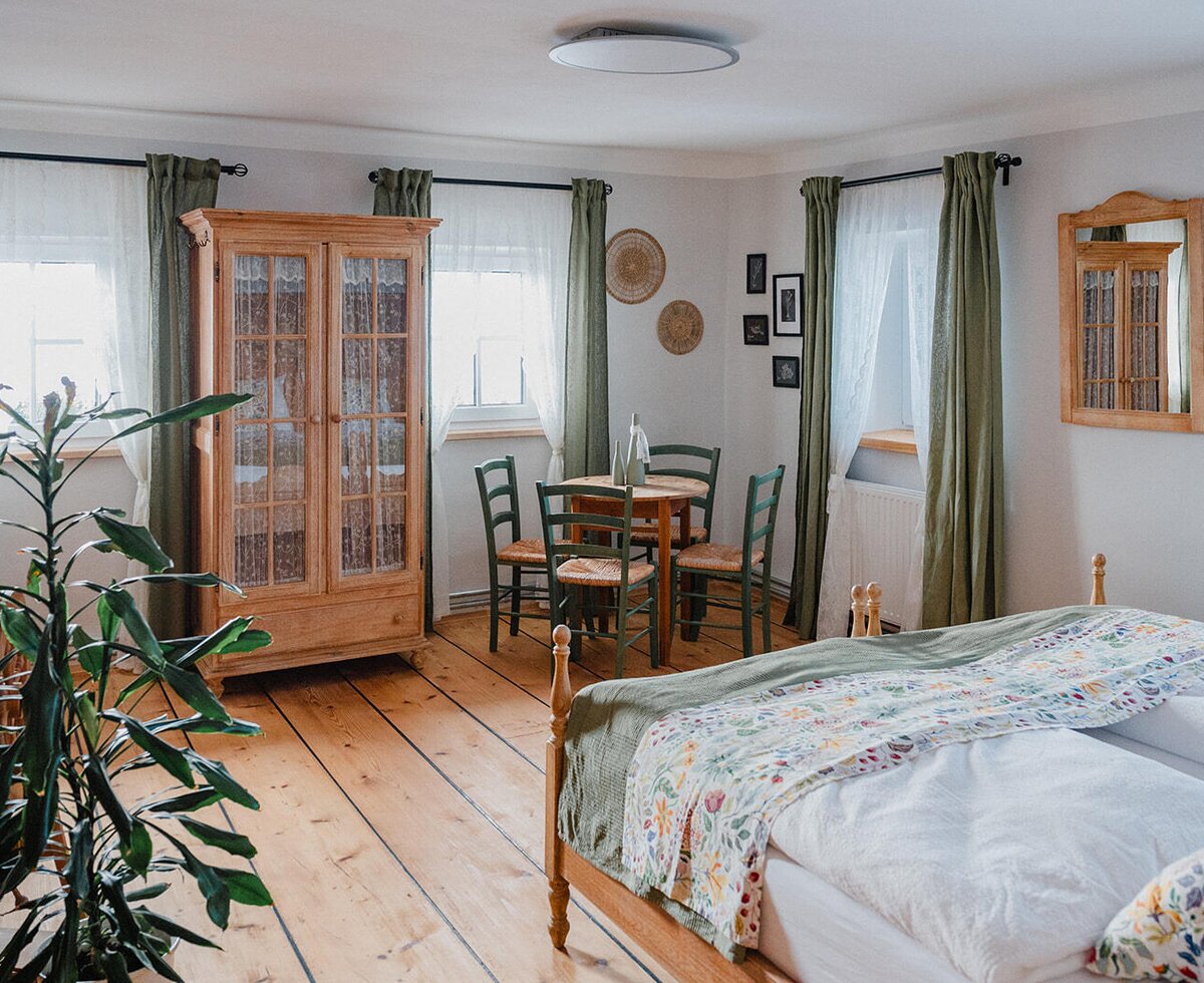 Bedroom in the Bed and Breakfast with a double bed, wooden floor, wooden wardrobe, and a small table with chairs.