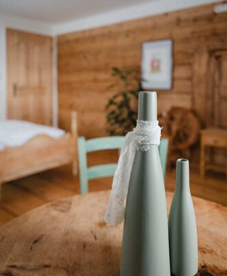 Decorative vases on a wooden table in the Bed and Breakfast bedroom, featuring wooden walls and a bed in the background.