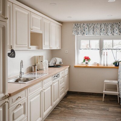 Kitchen in the Bed and Breakfast with white cabinets, sink, dishwasher, coffee maker, and window.
