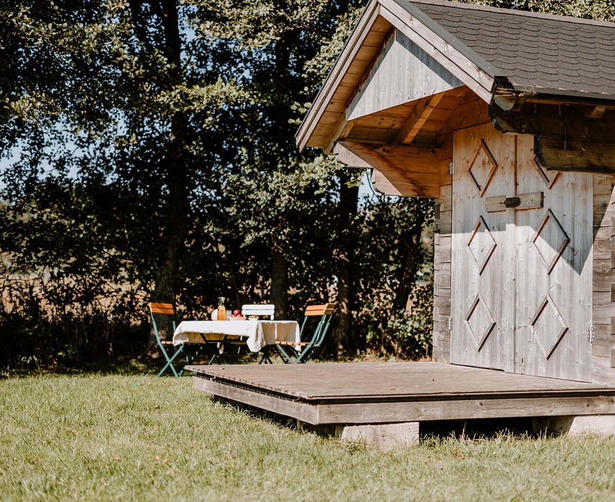 The garden area of the Bed and Breakfast, featuring a small wooden house, a terrace, and a set table for outdoor dining.